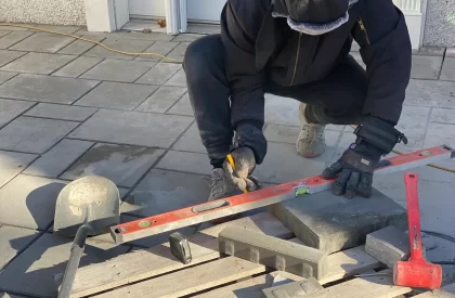 Homme mesurant une dalle pour l'installation d'un plancher dans un projet d'aménagement paysager
