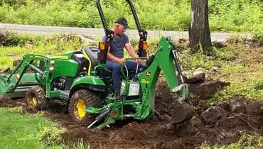 Un homme travaillant avec un tracteur chargeur pour nettoyer un terrain