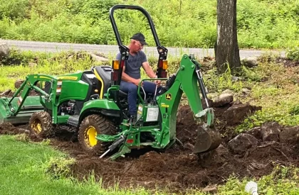 Un homme travaillant avec un tracteur chargeur pour nettoyer un terrain