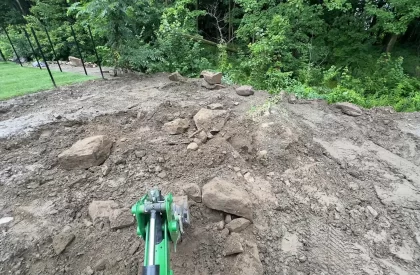 Pelle mécanique retirant des roches du sol lors de travaux d'aménagement paysager